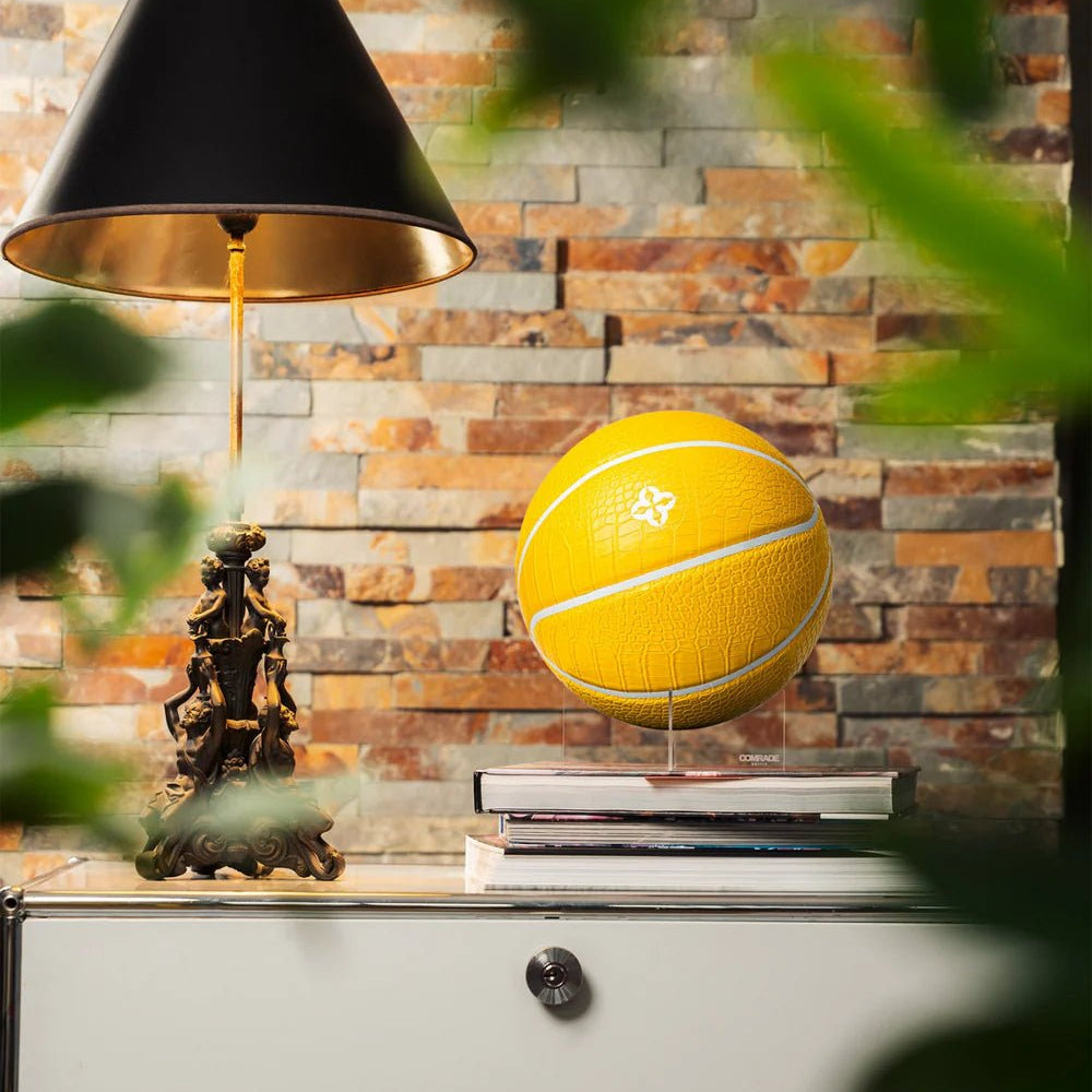 Geel basketbal op standaard met krokodillennerf en wit embleem